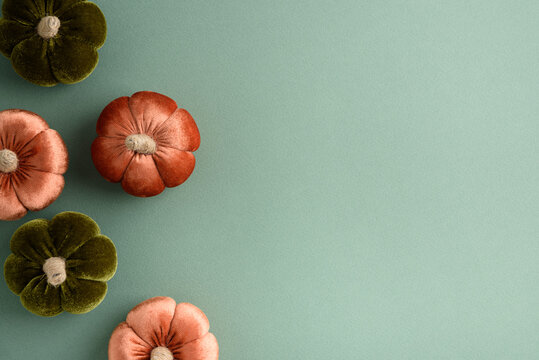 Decorative fabric pumpkins in autumnal colors arranged on a teal background
