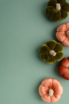 Decorated Velvet Pumpkins in Autumn Colors Arranged on a Teal Background