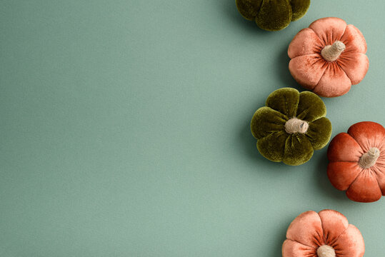 Soft fabric pumpkins in autumnal colors arranged on a plain background for seasonal decoration