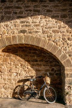 View of a bicycle with a wicker basket parked against an old stone wall with an archway in Essaouira, Marrakesh-Safi, Morocco.