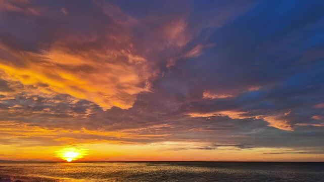 Timelapse of golden sunset with drifting clouds over calm black sea horizon in batumi.