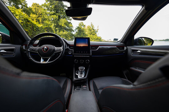 Renault Arkana RS Line cockpit view shows flat bottom wheel with RS badge, vertical infotainment tablet, aluminum pedals, bucket seats, and ambient light strips in daylight.