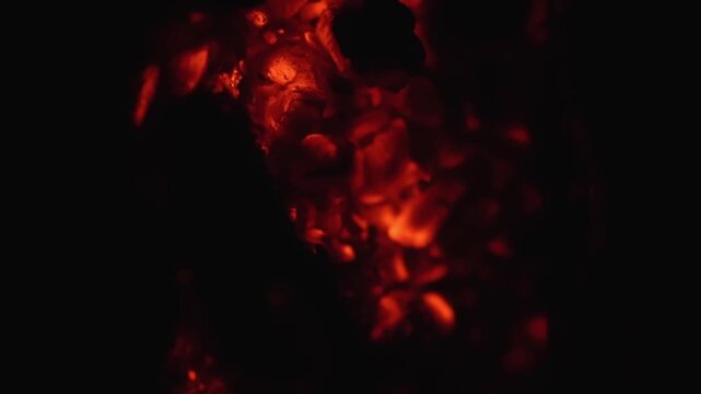 Macro shot of smoldering coals, illuminating textures and fading flames.