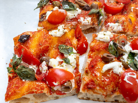 Colorful tray pizza or pinza in artisanal bakery in Rome, food of Italy, street food for lunch, with tomatoes, salami, basil, mozzarella