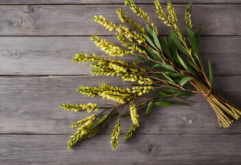 Obraz premium Bundle of yellow flowering acacia branches with green leaves on a rustic wooden background, natural decor concept, this natural arrangement provides a charming decor element