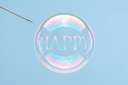 Soap bubble with the word happy and a needle about to pop it