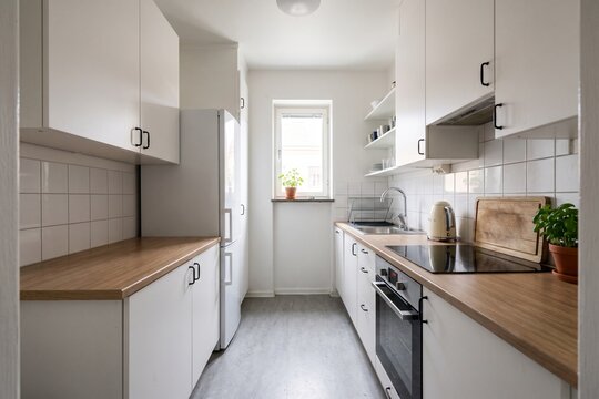 Narrow white kitchen interior with wooden countertops and clean design
