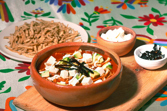 Mexican aztec soup with fried tortilla strips, diced avocado, queso fresco, and dried chili pepper garnish. Retro style