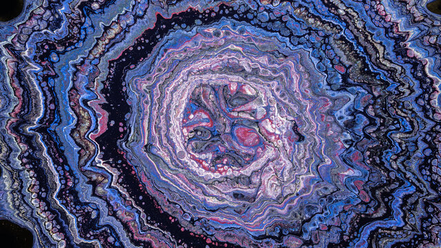 Concentric fluid acrylic pour forming marbled geode pattern in blue and purple tones