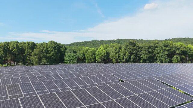 Drone flying forward above a large solar farm and forest