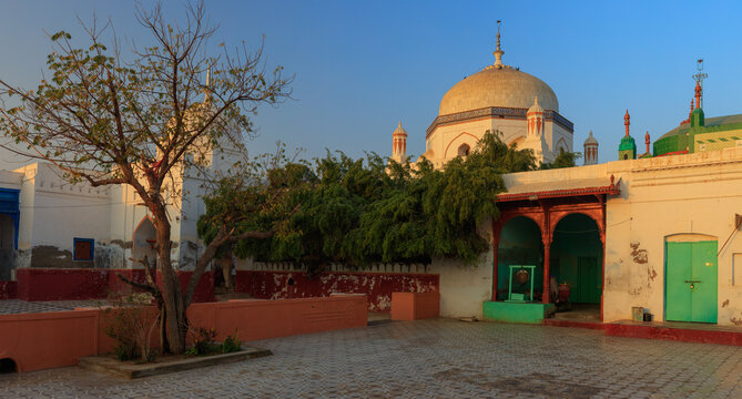 View of Udero Lal Mandir with its white dome, arched entrance, and courtyard, set against a clear blue sky in Juma Khan Kalhoro, Sindh, Pakistan.