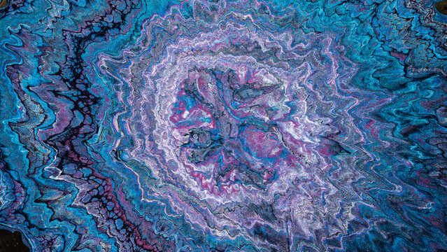 Abstract swirl of blue and purple paint with crystalline center and radial texture