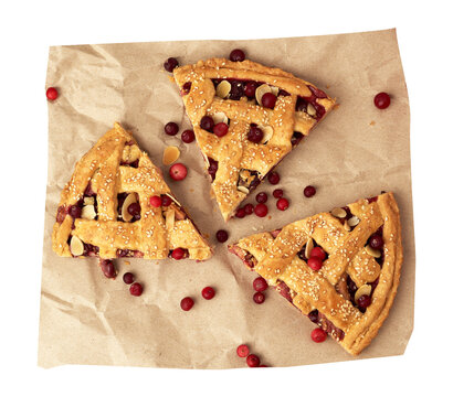 Three pieces of homemade pie with lingonberries, sesame seeds and almonds on craft paper.
