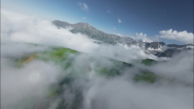 FPV flight through clouds over green mountains and snow-capped peaks