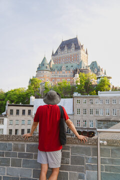 View of a person in a red shirt and hat looking at the historic Chateau Frontenac in Quebec City, Quebec, Canada.