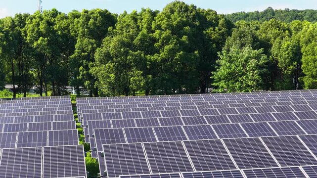 Drone moving over solar panels at the edge of a forest