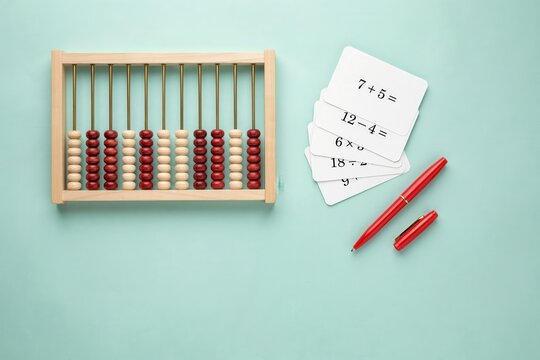Wooden abacus with math flashcards and red pen on blue background