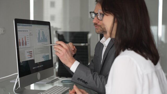 Business professionals collaborating and discussing information on a computer screen during a meeting in an office setting, actively engaging in teamwork and strategic planning. Businesspeople concept