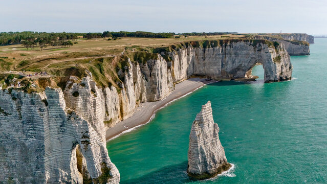 Wide aerial view of dramatic cliffs with a natural arch and sea stack formation