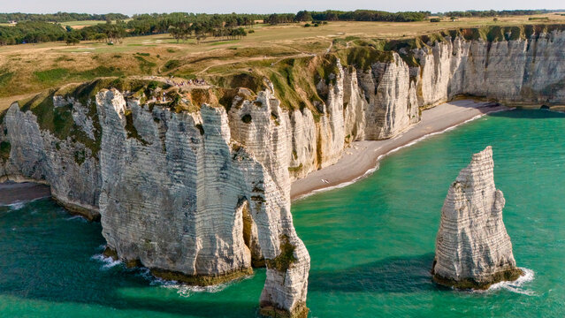 Close aerial view of a natural rock arch and sea stack surrounded by clear turquoise water