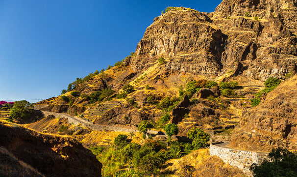 View of the winding road and stone retaining wall carved into the rugged mountains of Santo Antao in Alto Mira, Porto Novo, Cabo Verde.