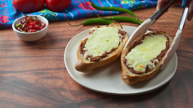 Gourmet Mexican Molletes with refried beans and melted mozzarella cheese on rustic wooden background