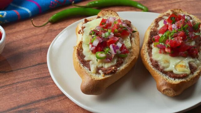 Traditional Mexican Molletes with pico de gallo on rustic wooden table