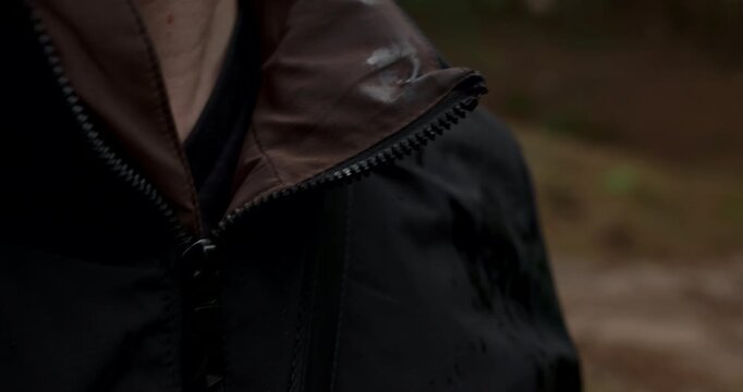 Close up of wet waterproof jacket with rain drops during forest hike