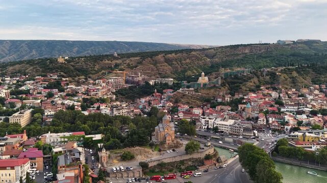 Breathtaking drone shot of Old Tbilisi, Georgia's top tourist attraction, showcasing iconic historic sightseeing landmarks like the cliffside Metekhi Church, ancient Narikala Fortress