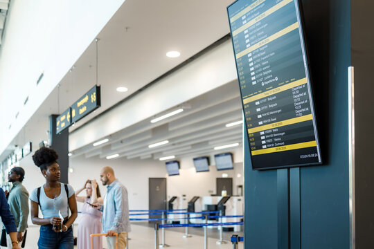 Airport scene with travelers checking flight information on a screen