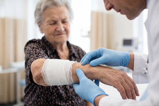 Doctor examining senior woman bandaged arm in clinic