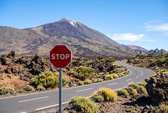 Stop sign along empty road near mount teide volcano landscape