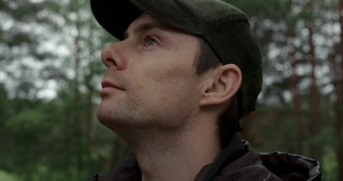 Close up portrait of man taking a deep breath of fresh air in forest and looking around