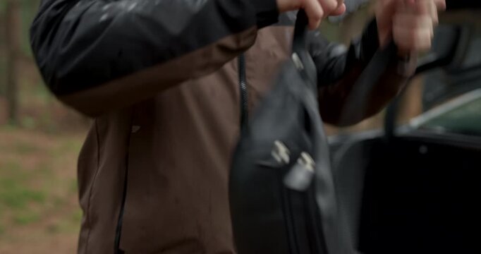 Close up of man zipping up waterproof jacket in rainy forest with audio included