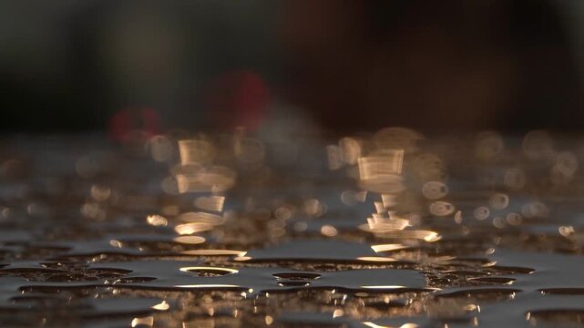 Sunset sunlight shines on transparent raindrops on a wooden surface, blurry background