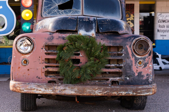Rusty vintage truck with a pine wreath parked along historic Route 66 in Seligman, Arizona. Concept of roadside Americana, vintage vehicles, nostalgic travel, and preservation of historic landmarks