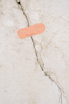 Cracked wall with band-aid placed on it showing an attempt to fix the damage
