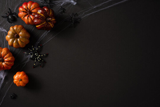 Happy Halloween pumpkins and spooky spider web decorations on black background for seasonal design