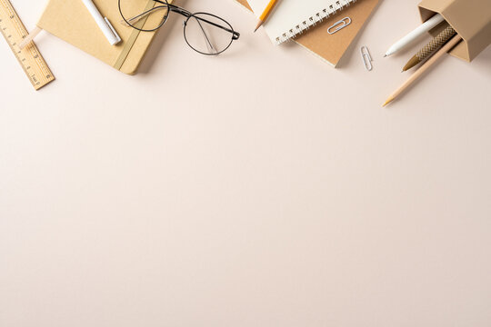 Back to school flat lay with neutral stationery, notebooks, pencils and glasses on desk