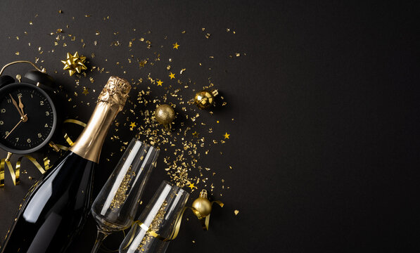Happy New Year 2027 celebration with champagne bottle, flutes and golden confetti on black background