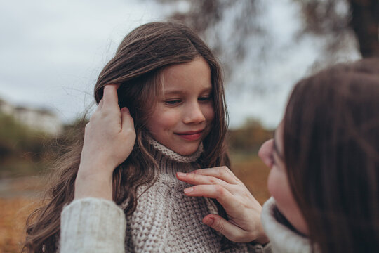 Tender moment between mother and daughter during autumn walk. Maternal love, affection, emotional connection, gentle care, mother's day, loving atmosphere.