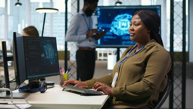 Female administrator trains artificial intelligence and deep learning models on a computer, using neural networks to optimize performance and forecast technical issues in an office environment.