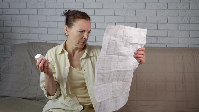 Confused woman reading long medical prescription instructions. Frustrated woman sitting on a sofa reading the long and complicated instructions for her medication, then angrily crumpling the paper