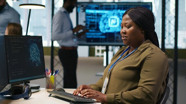 Female technician writes code and develops neural network APIs on a computer, troubleshooting software errors with artificial intelligence tools during application testing and maintenance.