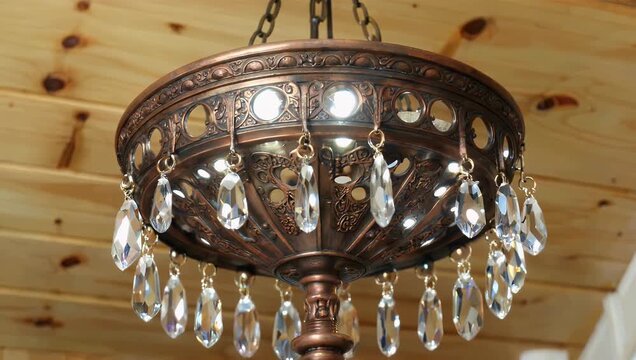 High quality 4K interior b roll footage highlighting elegant decorative copper hanging lamps adorned with sparkling crystals suspended from a rustic wooden ceiling while emitting a warm luxurious