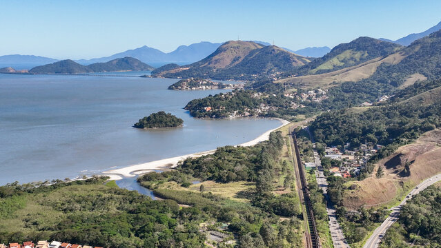 Reserva do Sahy, Condado, featuring modern residential houses nestled between lush green hills and the calm ocean waters in Mangaratiba, Rio de Janeiro, Brazil. Aerial view.