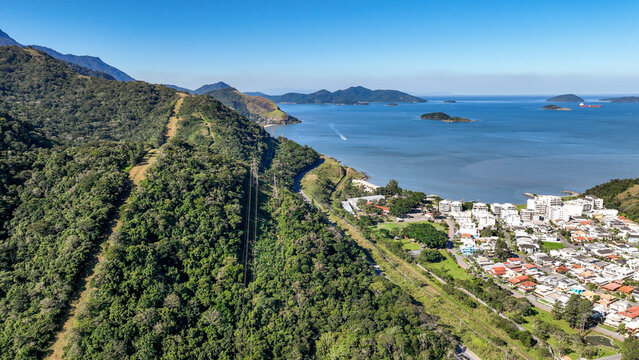 Reserva do Sahy, Condado, featuring modern residential houses nestled between lush green hills and the calm ocean waters in Mangaratiba, Rio de Janeiro, Brazil. Aerial view.