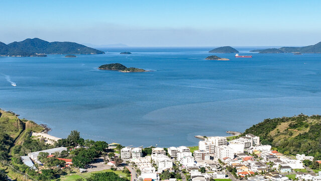 Reserva do Sahy, Condado, featuring modern residential houses nestled between lush green hills and the calm ocean waters in Mangaratiba, Rio de Janeiro, Brazil. Aerial view.