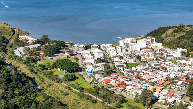 Reserva do Sahy, Condado, featuring modern residential houses nestled between lush green hills and the calm ocean waters in Mangaratiba, Rio de Janeiro, Brazil. Aerial view.
