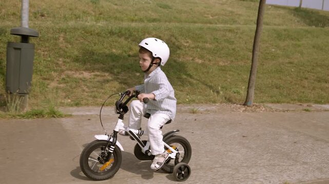 Young boy learning to ride bicycle with training wheels in park